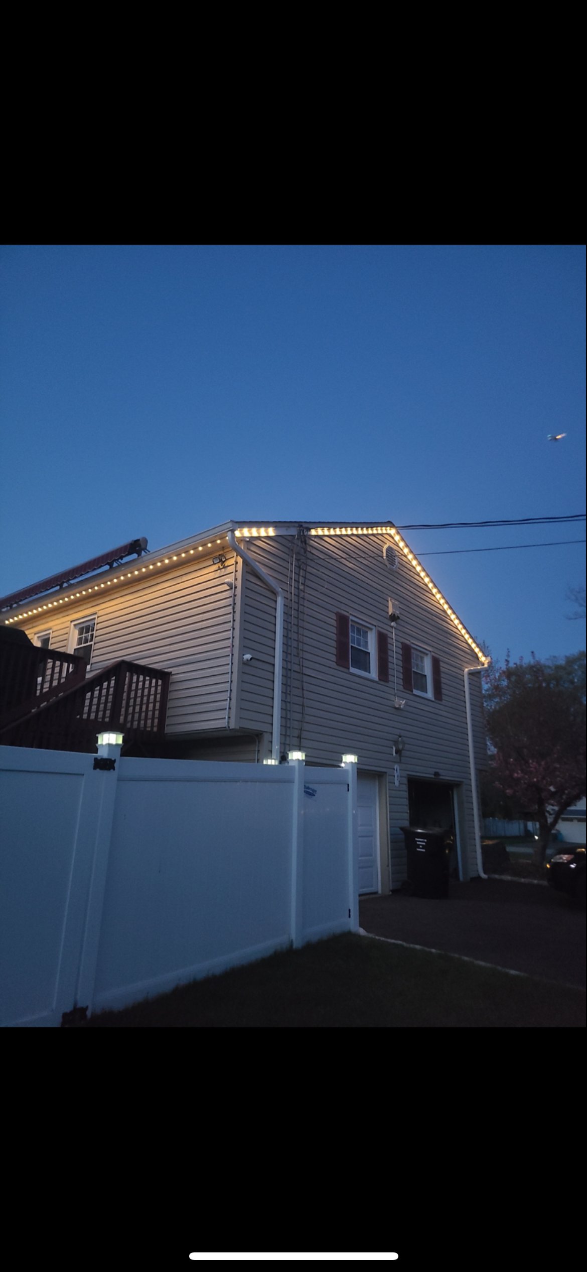 Warm white lights installed along the roofline of a residential property