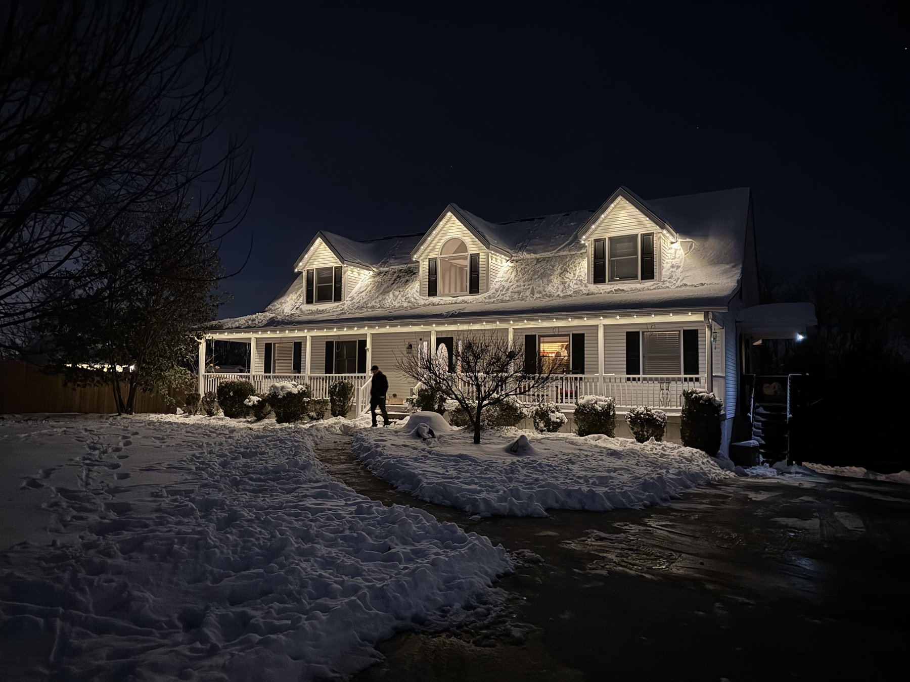 Warm white holiday lights installed on a snow-covered North Jersey home