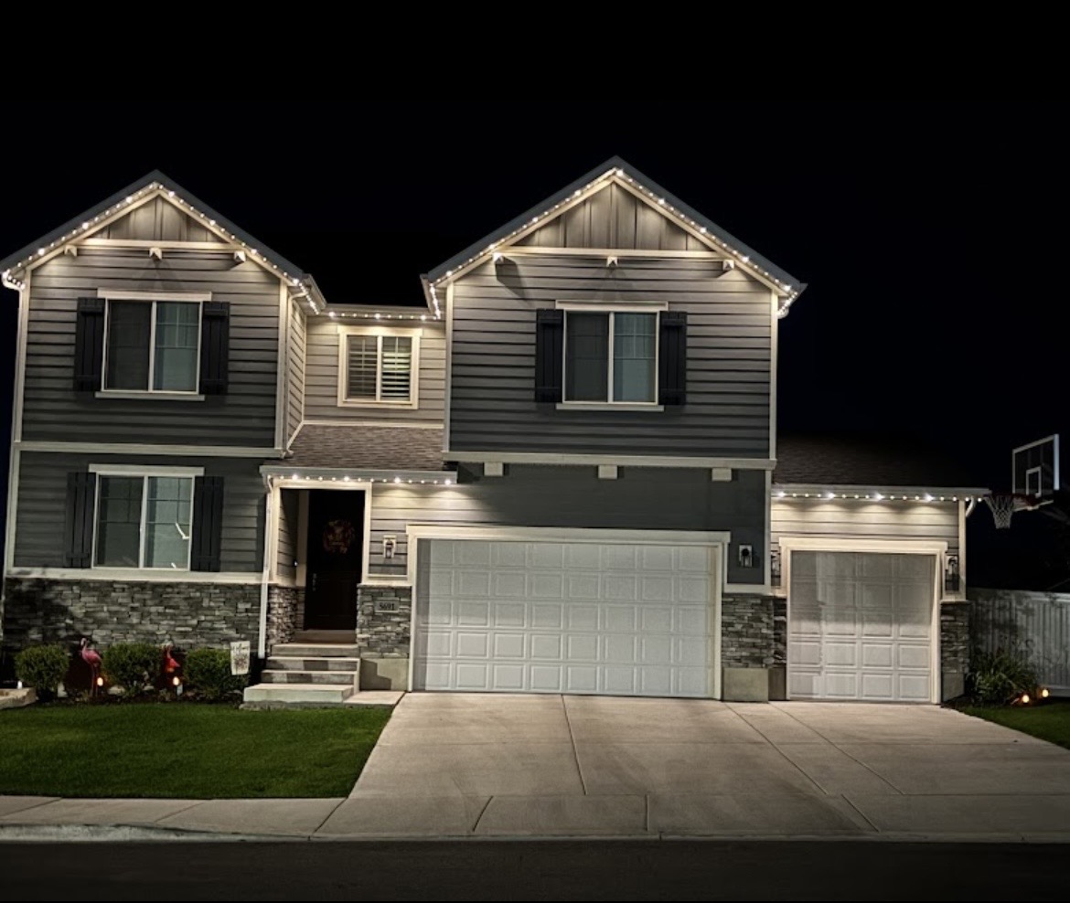 Warm white permanent exterior lights on a gray two-story home