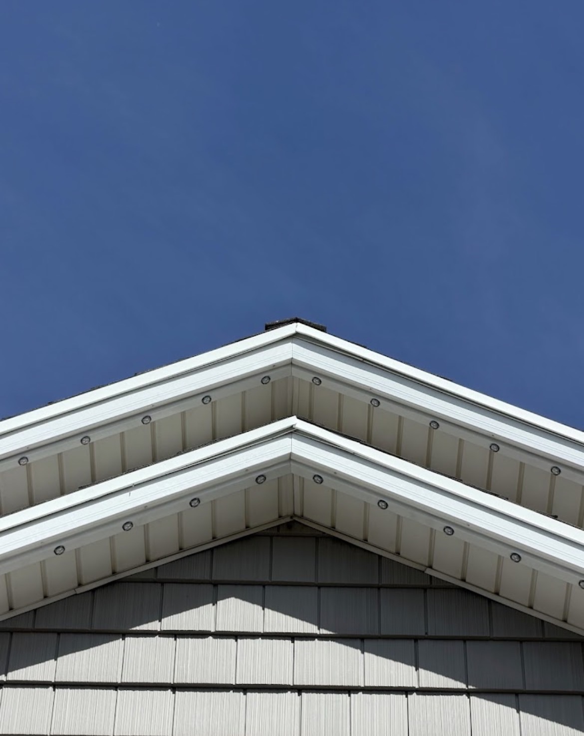 Permanent LED pucks mounted discreetly beneath white residential eaves in daylight