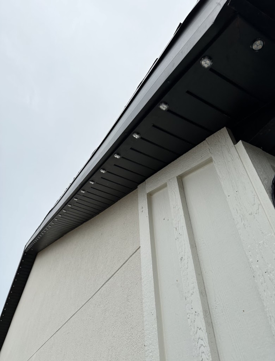 Close view of evenly spaced permanent LED pucks mounted beneath dark eaves