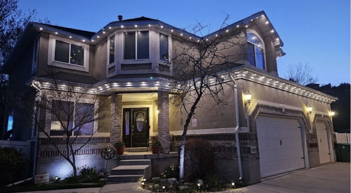Warm white permanent LED lights installed around a two-story home and garage